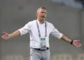 Antoine Hey gestures on the touchline during a match, wearing a white shirt and lanyard, as he takes charge of Algerian club ES Sétif.