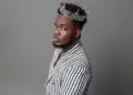 Liberian artist CIC wears a silver crown and a striped suit, embodying his “Local Champion” persona in a powerful promotional portrait for his 2025 album release.
