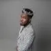 Liberian artist CIC wears a silver crown and a striped suit, embodying his “Local Champion” persona in a powerful promotional portrait for his 2025 album release.
