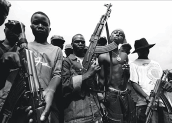 Former Liberian combatants holding assault rifles during the civil war, symbolizing the legacy of violence that transitional justice efforts aim to address.