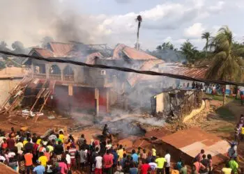 Crowds watch as smoke rises from a destroyed home and storage facility during a major fire in Pleebo City, Maryland County, Liberia