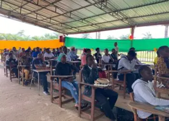 Over 100 Tubman University students seated in pavilion-turned-lecture hall as enrollment surge pushes administrators to expand learning spaces.