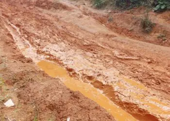 A muddy, impassable rural road in Garyea Clan, Bong County, showing deep erosion and stagnant water after heavy rains