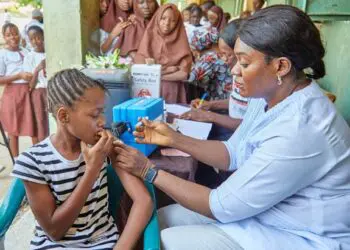 Health worker in Liberia administers HPV vaccine to a school-aged girl as part of the national cervical cancer prevention campaign.