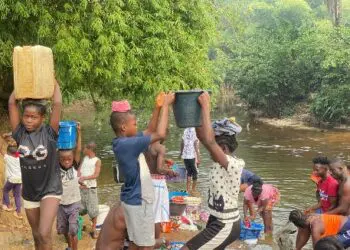 Residents of Morris Farm Community in Todee District, Rural Montserrado County, fetch water and wash clothes at a creek along the Du River due to limited access to hand pumps.