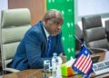 Former Finance Minister Samuel D. Tweah Jr. speaking at a meeting with the Liberian flag and EU flag on the table.