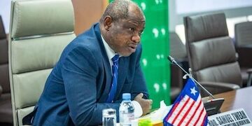 Former Finance Minister Samuel D. Tweah Jr. speaking at a meeting with the Liberian flag and EU flag on the table.