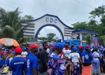 Entrance gate of the Congress for Democratic Change (CDC) headquarters in Congo Town, Monrovia, with party colors and signage clearly visible on a quiet street.
