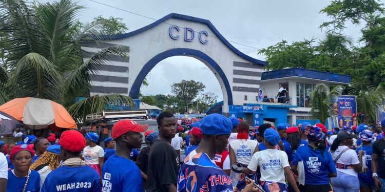 Entrance gate of the Congress for Democratic Change (CDC) headquarters in Congo Town, Monrovia, with party colors and signage clearly visible on a quiet street.