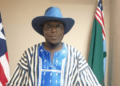 a man wearing hat standing with two flags behind him