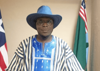 a man wearing hat standing with two flags behind him