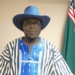 a man wearing hat standing with two flags behind him