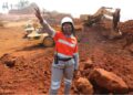 A female miner worker standing with and hand in the air