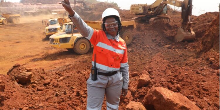 A female miner worker standing with and hand in the air