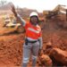 A female miner worker standing with and hand in the air