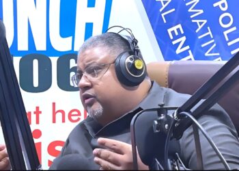 Amin Modad speaking into a microphone during a live radio interview, addressing his resignation as Liberia’s Minister of Commerce.