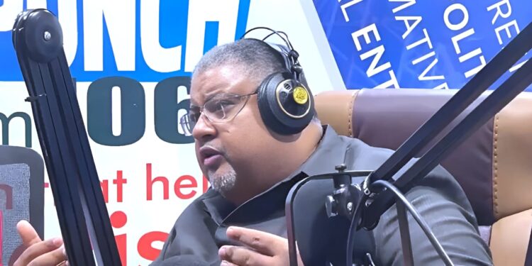 Amin Modad speaking into a microphone during a live radio interview, addressing his resignation as Liberia’s Minister of Commerce.