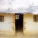 Cracked mud-walled Gbi-Doru Courthouse with thatched roof, lacking basic infrastructure