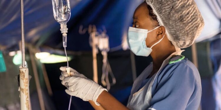 Liberian nurse adjusts IV drip inside a makeshift hospital tent,