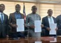 Government officials hold signed MOU documents during the launch of Liberia’s first National Digital Health Insurance Pilot for vulnerable citizens.