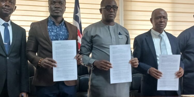 Government officials hold signed MOU documents during the launch of Liberia’s first National Digital Health Insurance Pilot for vulnerable citizens.