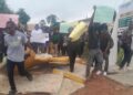 Students at the Lutheran University of Liberia protest by blocking an entrance with worn-out mattresses and holding handwritten signs, demanding better dormitory conditions and academic services.