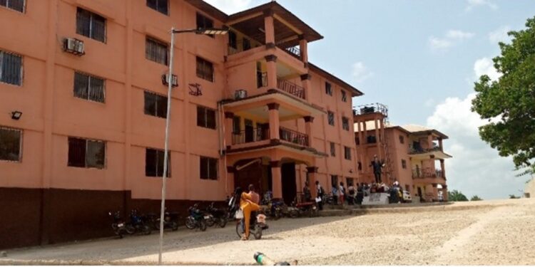 Front view of Prince Y. Johnson Polyethnic University in Ganta, Liberia, with students and motorcycles gathered outside during closure