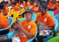 UBCAA computer literacy graduates in orange shirts seated during graduation ceremony in Gbarnga, Bong County