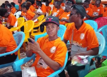 UBCAA computer literacy graduates in orange shirts seated during graduation ceremony in Gbarnga, Bong County