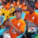 UBCAA computer literacy graduates in orange shirts seated during graduation ceremony in Gbarnga, Bong County
