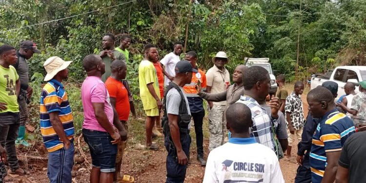 Local residents, mining company workers, and officials gather in Gbakonai, Bong County, during a government-led community engagement to address a mining license dispute between H&K Mining and Da-Tahn Company.