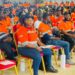 Liberian workers in orange uniforms seated during an ArcelorMittal Liberia employee event, showcasing local workforce engagement and company transparency.