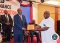 President Joseph Boakai presents a performance certificate to LACRA Director General Christopher Sankolo during the 2024 PMCS awards ceremony in Monrovia.