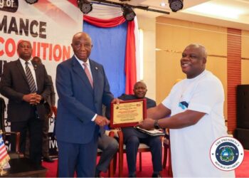 President Joseph Boakai presents a performance certificate to LACRA Director General Christopher Sankolo during the 2024 PMCS awards ceremony in Monrovia.
