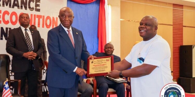 President Joseph Boakai presents a performance certificate to LACRA Director General Christopher Sankolo during the 2024 PMCS awards ceremony in Monrovia.