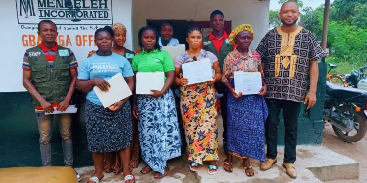 Women and youth in Bong County proudly hold land deeds awarded by Menleleh Incorporated during land rights ceremony