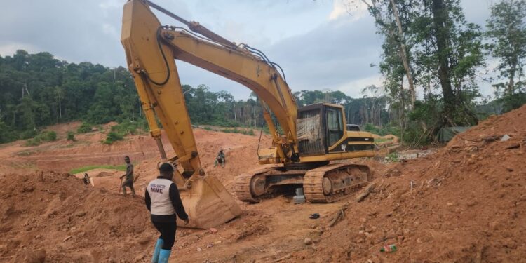 An excavator at an illegal mining site in Duogbo Town, Grand Kru County, as a Ministry of Mines official supervises its shutdown.