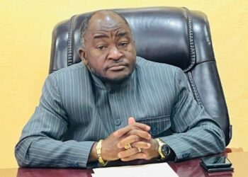 Ambassador Dee-Maxwell Saah Kemayah, Sr., seated behind a desk, hands clasped, wearing a striped traditional suit, addressing the public on Liberia’s election to the UN Security Council.”