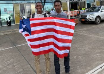 Douglas Sackor and Shaun Toteh hold a Liberian flag at the airport before departing for European football trials in Accra, Ghana.