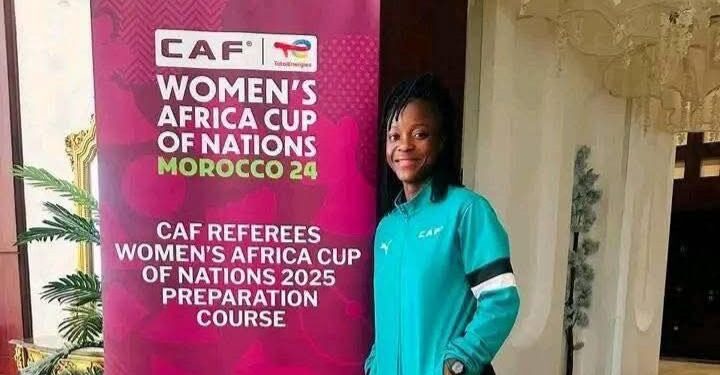 Liberian referee Hannah Moses stands beside a CAF Women’s Africa Cup of Nations preparation course banner during elite training in Cairo, Egypt.
