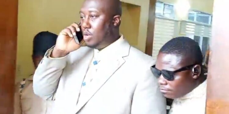 Al Hussein Fadiga, seen on the phone while being escorted by court officers, after his arrest and remand at Monrovia Central Prison on June 23, 2025, over a $1.6 million libel judgment.