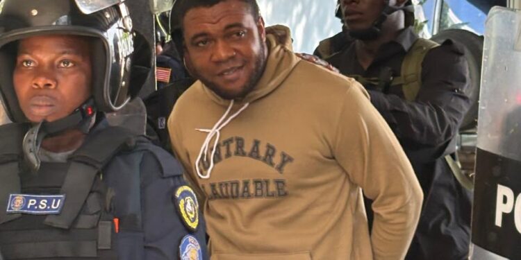 Capitol arson suspect John Nyanti in handcuffs escorted by heavily armed Liberian police officers, including a PSU officer in riot gear, outside the Temple of Justice in Monrovia.