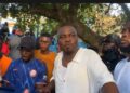 CDC National Treasurer Janga A. Kowo addresses a crowd of supporters under a tree in Monrovia, flanked by young men and party loyalists during a press engagement on the detention of opposition lawmakers