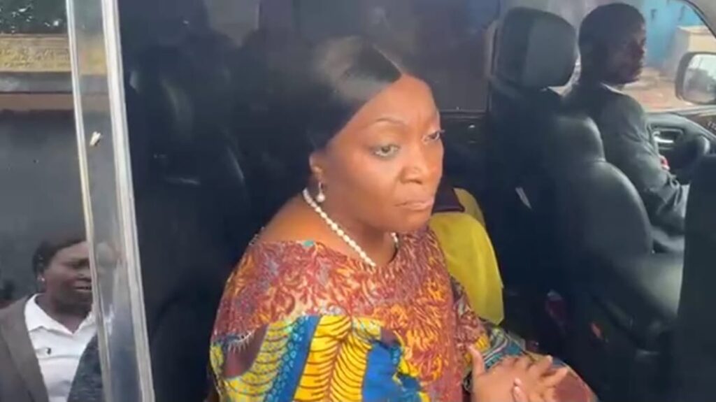 Former Vice President Jewel Howard-Taylor sits inside a vehicle, speaking to reporters after visiting jailed lawmakers at the Monrovia Central Prison, wearing a colorful traditional outfit and pearl necklace.
