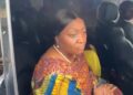 Former Vice President Jewel Howard-Taylor sits inside a vehicle, speaking to reporters after visiting jailed lawmakers at the Monrovia Central Prison, wearing a colorful traditional outfit and pearl necklace.