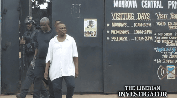 CDC Chairman Janga Augustus Kowo walks out of the Monrovia Central Prison after his release, escorted by security personnel, with the prison gate and visitation schedule visible in the background