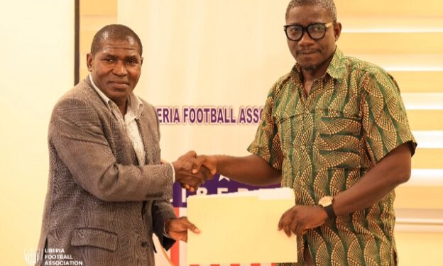 FA Deputy Secretary-General Muhammed Sheriff and NHSS Executive Director Dionysius Sebwe shake hands during the signing of a two-year grassroots football development partnership.