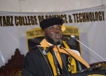 Starz University founder Ambassador Latim Da-Thong delivers a speech in academic regalia during a commencement ceremony, supporting NCHE reforms in Liberia’s higher education sector.