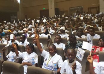 Hundreds of Liberian children raise UNICEF pamphlets at a youth gathering in Monrovia during Day of the African Child commemoration.