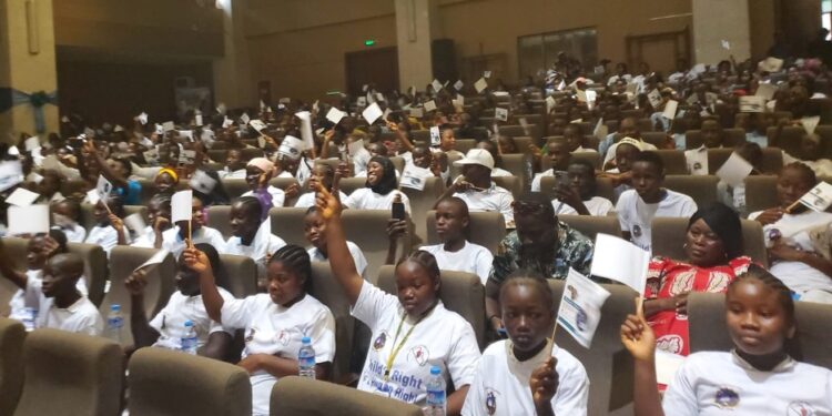 Hundreds of Liberian children raise UNICEF pamphlets at a youth gathering in Monrovia during Day of the African Child commemoration.
